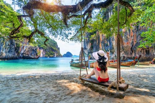 Woman in bikini relaxing on swing at Ko lao lading island, Krabi